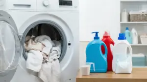 Lavatrice aperta con asciugamani e detergenti sul piano, per igienizzare e disinfettare il bucato